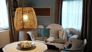 A cozy living room with a patterned lamp, a sofa with cushions, and a small table with a tray. - B&B de Valkenhorst (Lelystad)