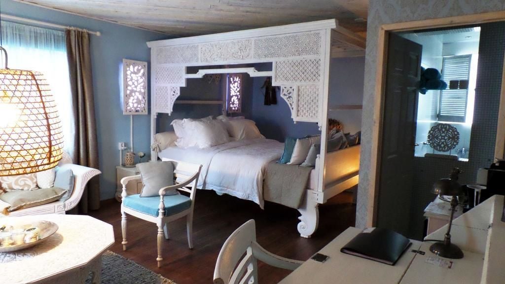 Ein Schlafzimmer mit einem Himmelbett, einem Schreibtisch mit einem Laptop und einem Stuhl.