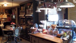 A kitchen with a wooden island, hanging pots, and a dining area with chairs and a table. - B&B de Valkenhorst (Lelystad)