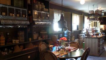 Une cuisine avec des meubles de rangement en bois, une table à manger, des chaises et divers appareils de cuisine.
