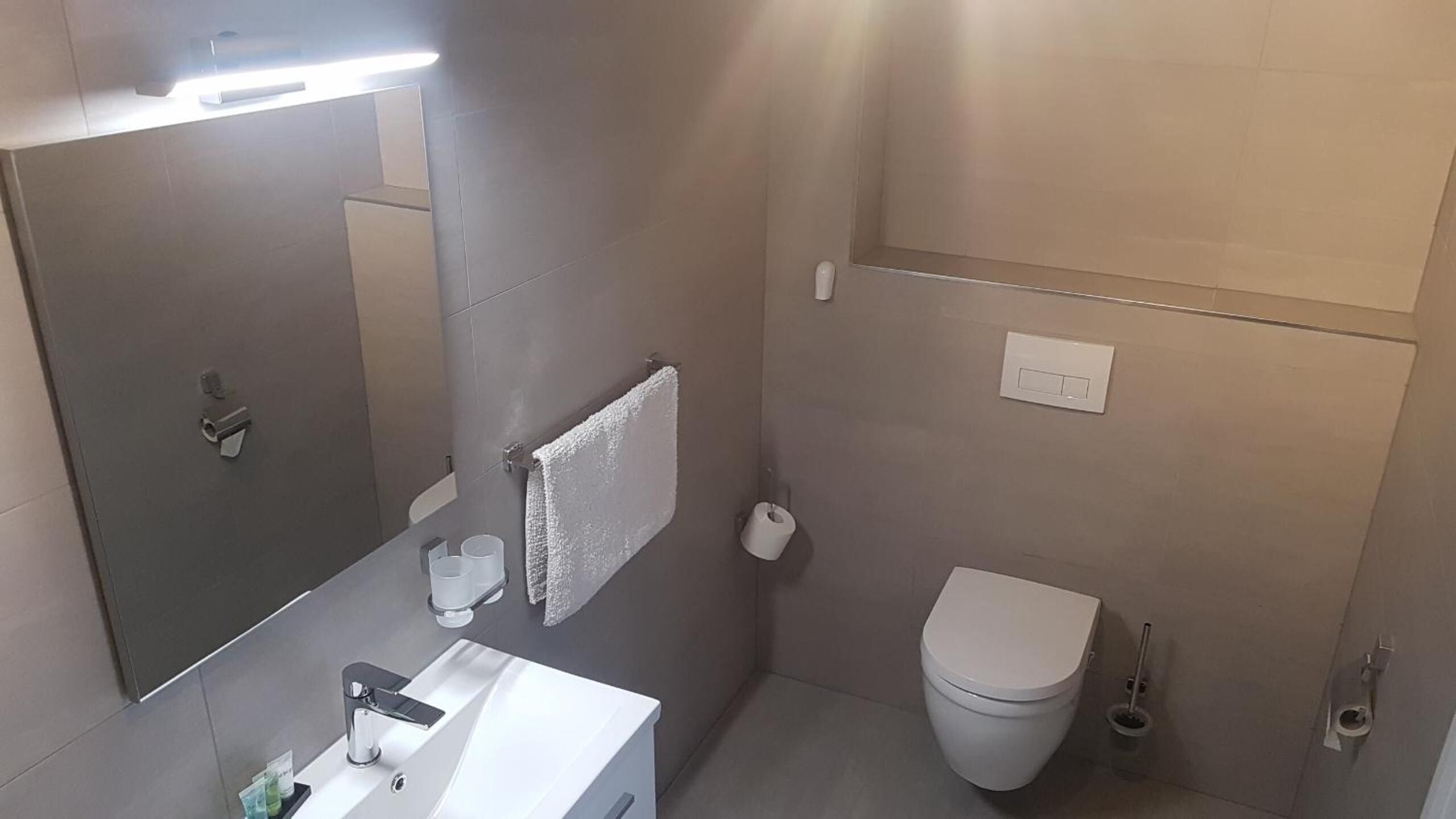 A modern bathroom with a toilet, sink, and mirror.
