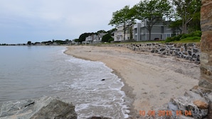 Une plage avec un mur de pierres et des maisons en arrière-plan.