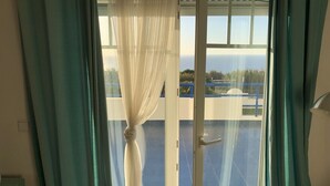 Une chambre avec vue sur une piscine bleue et un bâtiment situé de l’autre côté de l’eau.