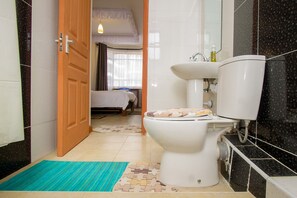 A bathroom with a toilet, sink, and a shower area. - City Airport Apartment Nairobi (Syokimau)