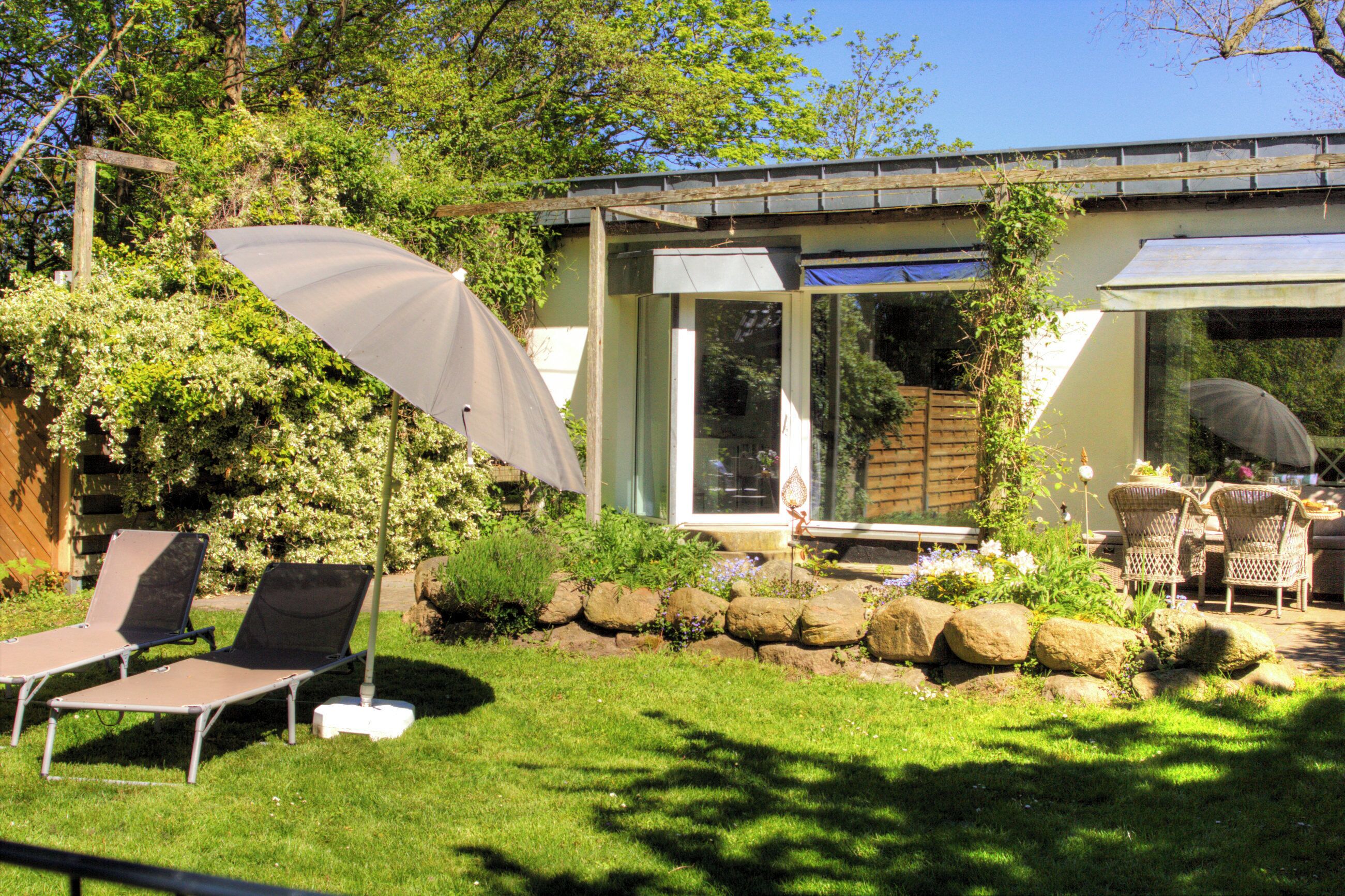 A patio with two lounge chairs, a table, and an umbrella.