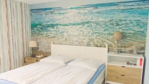 A bedroom with a bed, a nightstand, a lamp, and a bookshelf. - Vacation in peace & nature - apartment on the Bodden with fenced plot. & water access (Wiek)