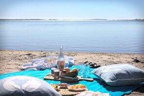 A beach setting with a picnic setup including food, drinks, and a bottle. - Vacation in peace & nature - apartment on the Bodden with fenced plot. & water access (Wiek)