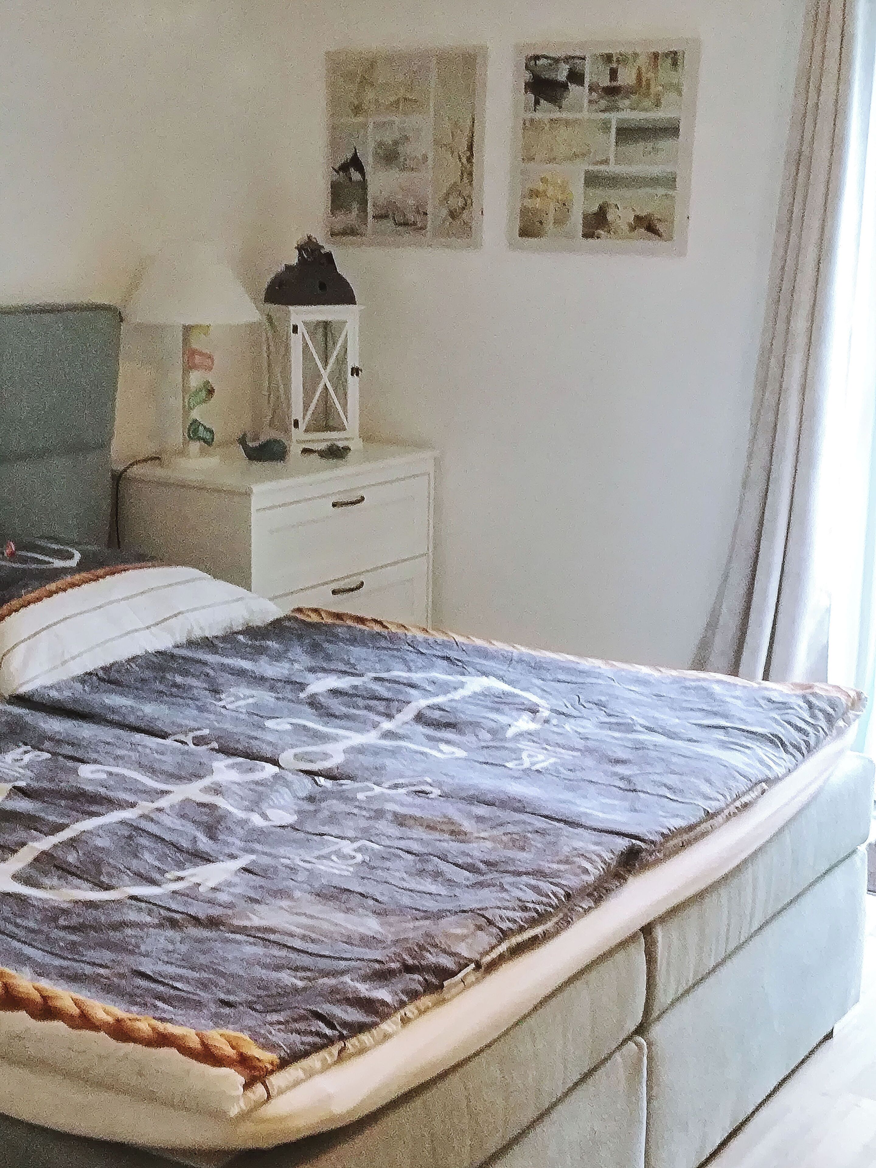 Quarto com uma cama, mesa de cabeceira, luminária e parede decorada com quadros.