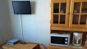 Een kleine keuken met een houten tafel, stoelen, een magnetron en een koffiezetapparaat.
