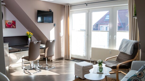 Una sala moderna con un sofá, un sillón y una mesita con un florero.