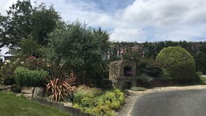 A garden with a stone archway, lush greenery, and a paved path. - GITE 3 EPIS BETWEEN LAMBALLE AND PLANCOET FOR 8 PERSONS (saint denoual)