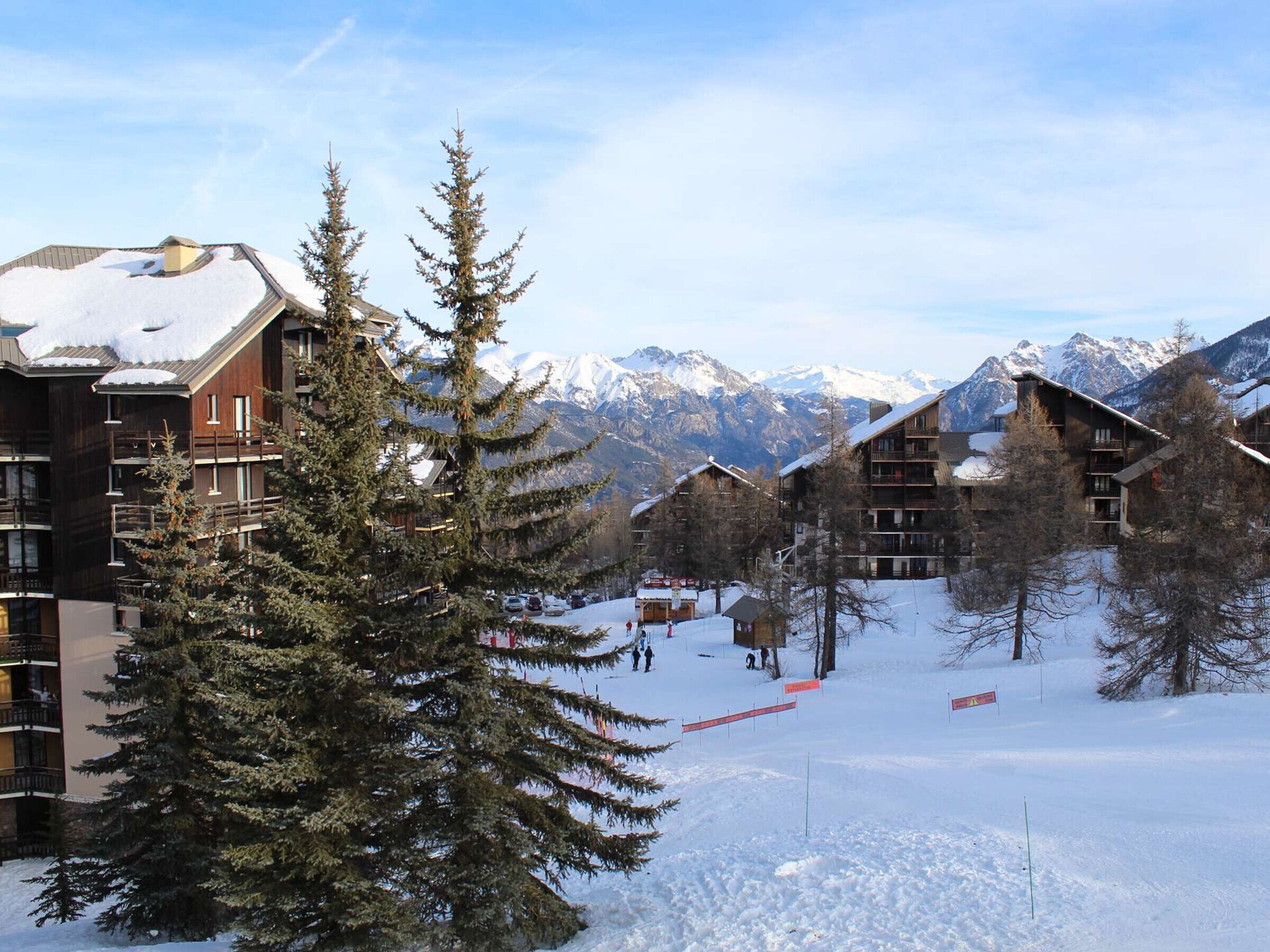 A snow-covered mountain resort with wooden buildings and pine trees.