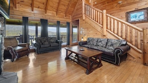 A spacious wooden interior with a high ceiling, a staircase, and a large window overlooking a scenic view. - Mountain Views!3 miles to Pkwy,pools,putt golf,Game Room,HotTub,ColdAC topflr (Sevierville)