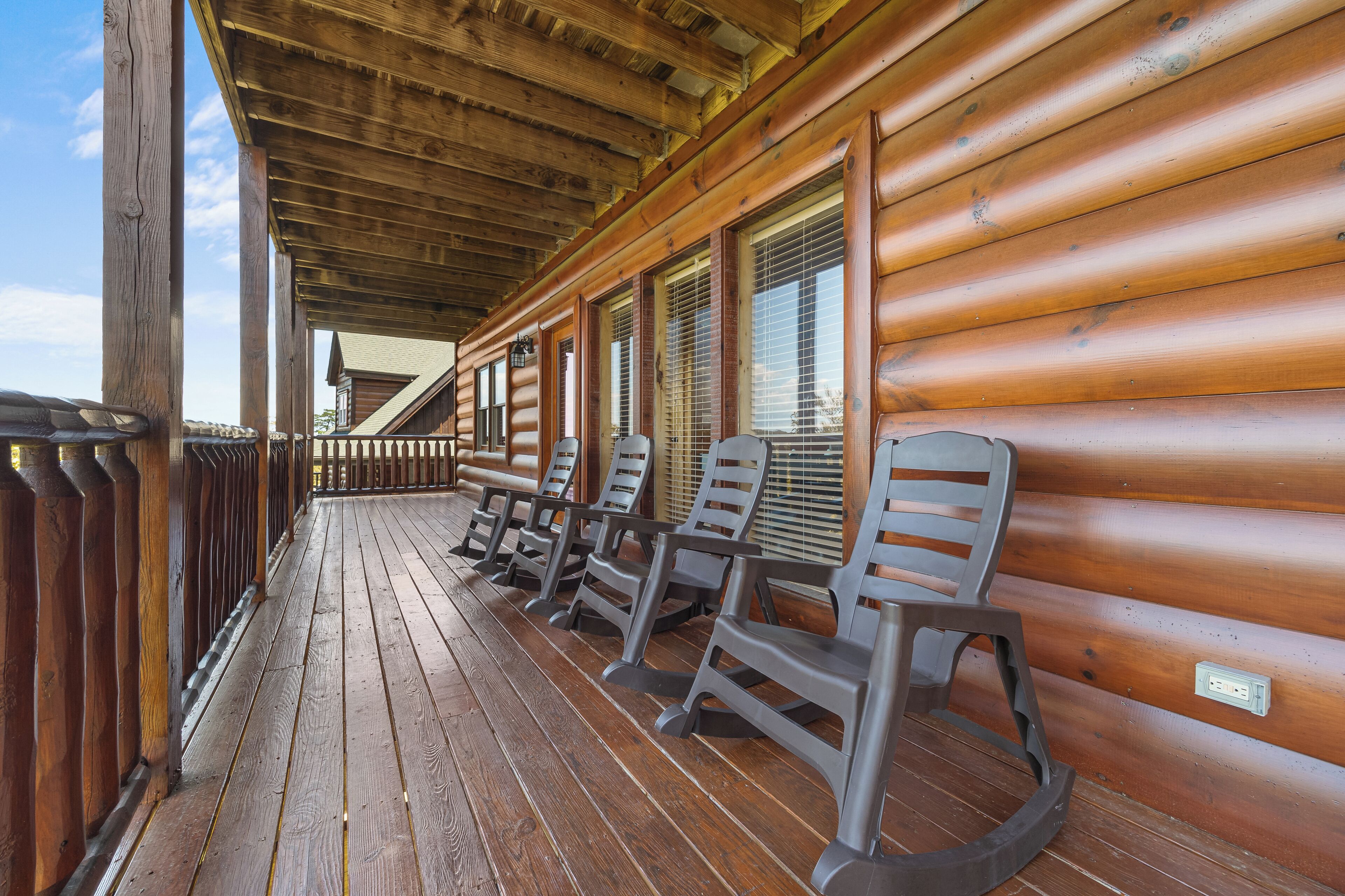 A wooden porch with rocking chairs and a wooden railing.