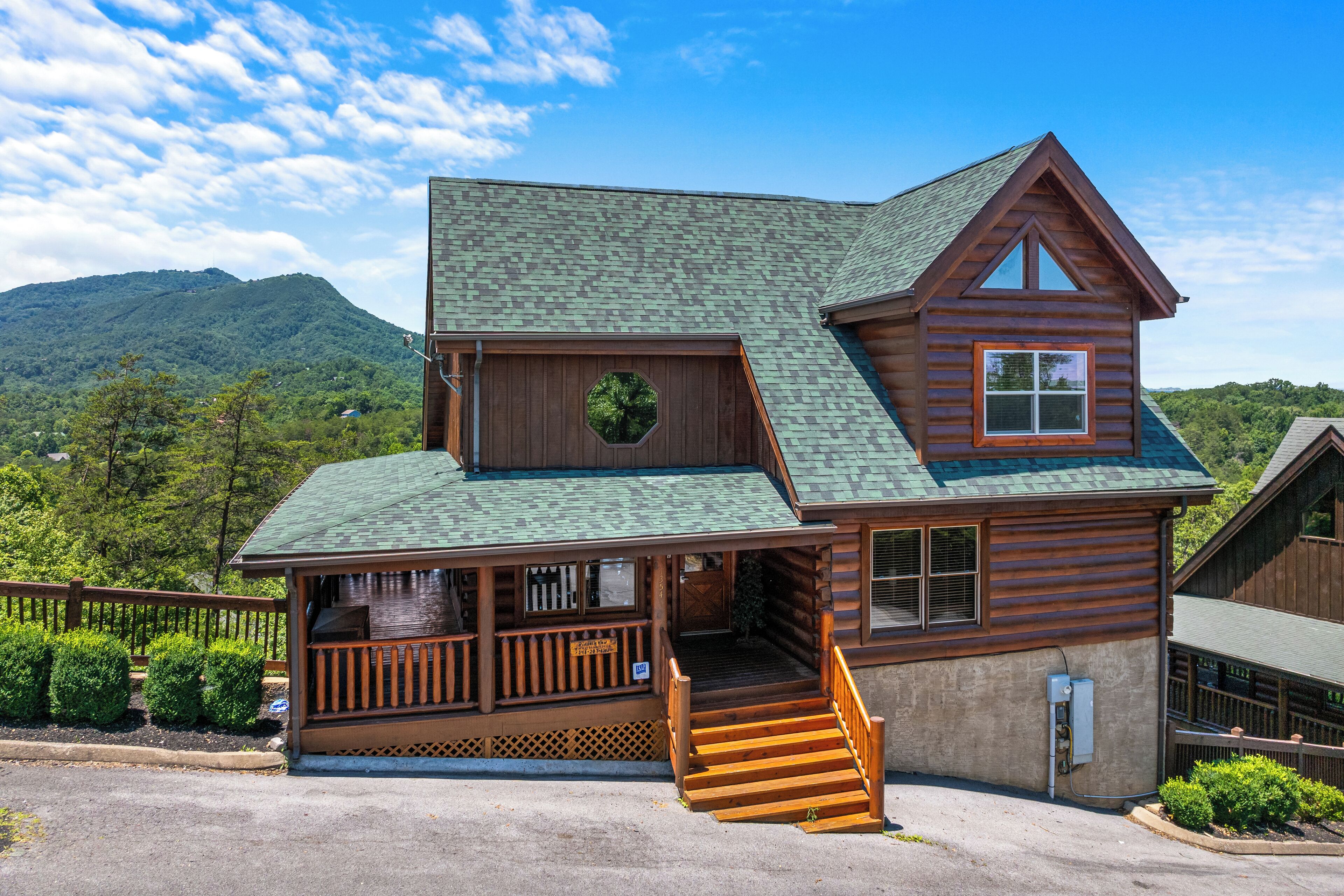 Une cabane en rondins avec un porche, un escalier et une vue sur les montagnes.