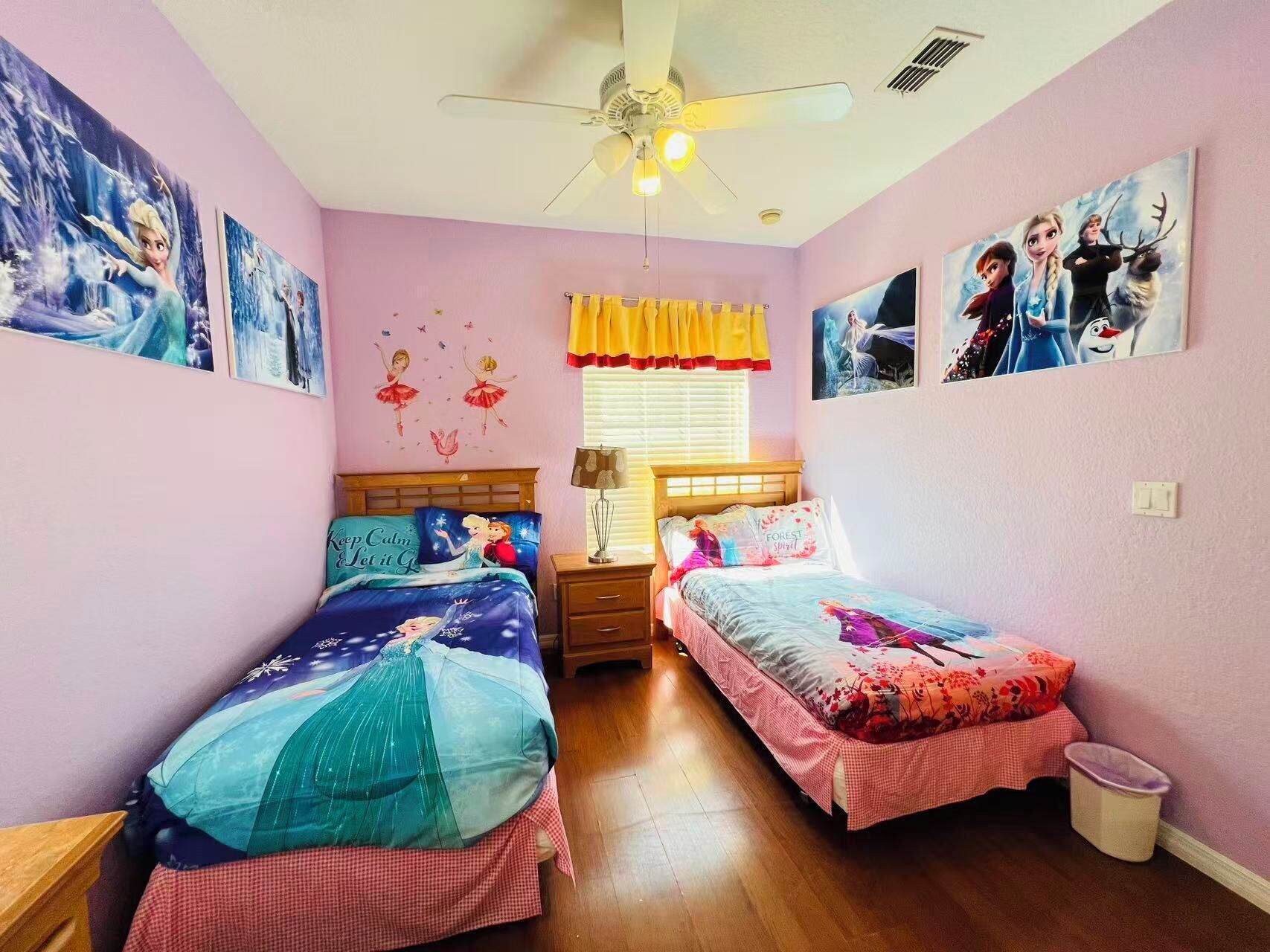 Ein Schlafzimmer mit zwei Betten, einem Deckenventilator und Wandbildern.