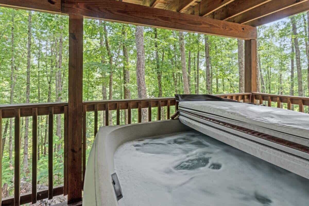 A wooden deck with a hot tub and a metal railing.
