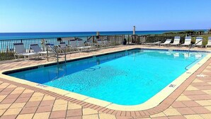 Una piscina rectangular con agua cristalina y azul, rodeada por una terraza con baldosas y sillas de descanso.