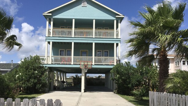 A two-story building with a balcony on the upper floor, a visible satellite dish, and a concrete pathway leading to the entrance. - beachouse 1/2block to convention center/ restaurants/bars (Galveston)