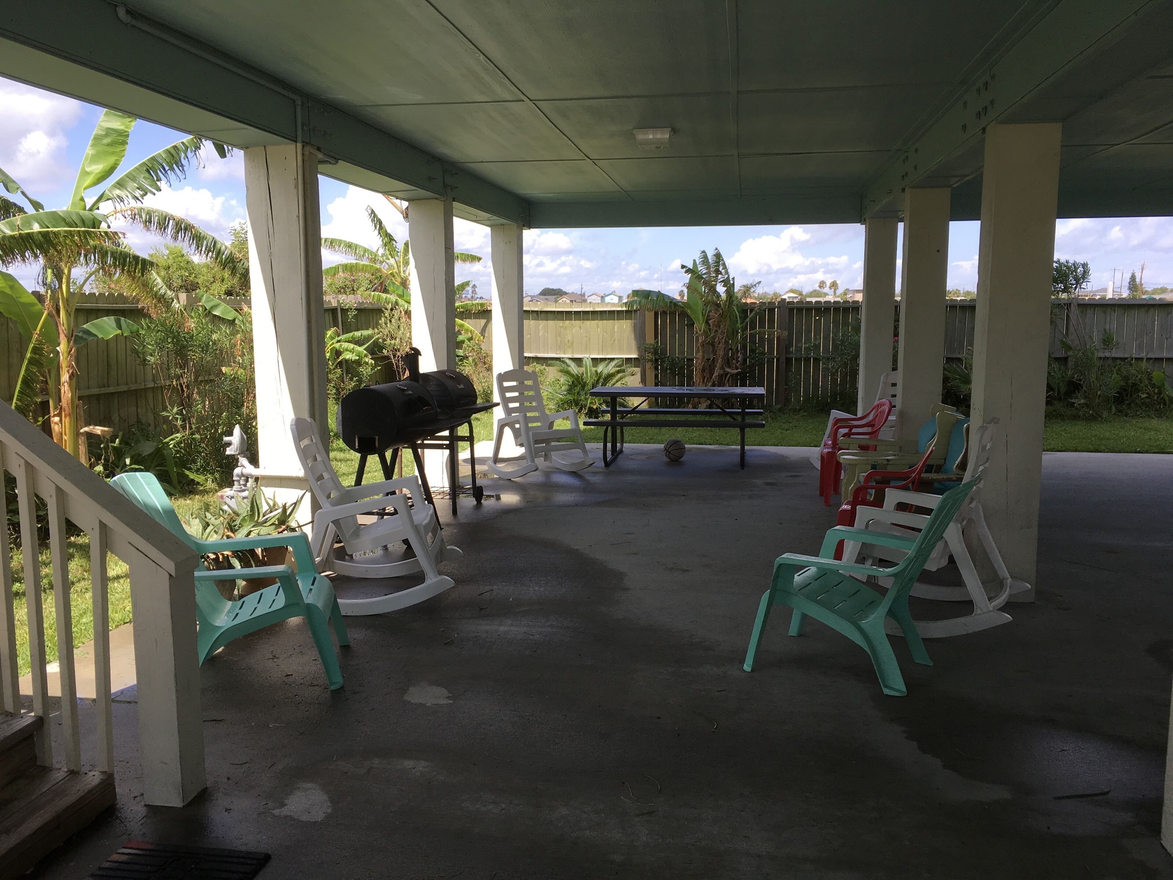 A covered patio area with a barbecue grill, picnic table, and outdoor seating.