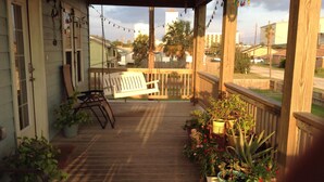 A wooden porch with a bench, potted plants, and a view of the neighborhood. - beachouse 1/2block to convention center/ restaurants/bars (Galveston)
