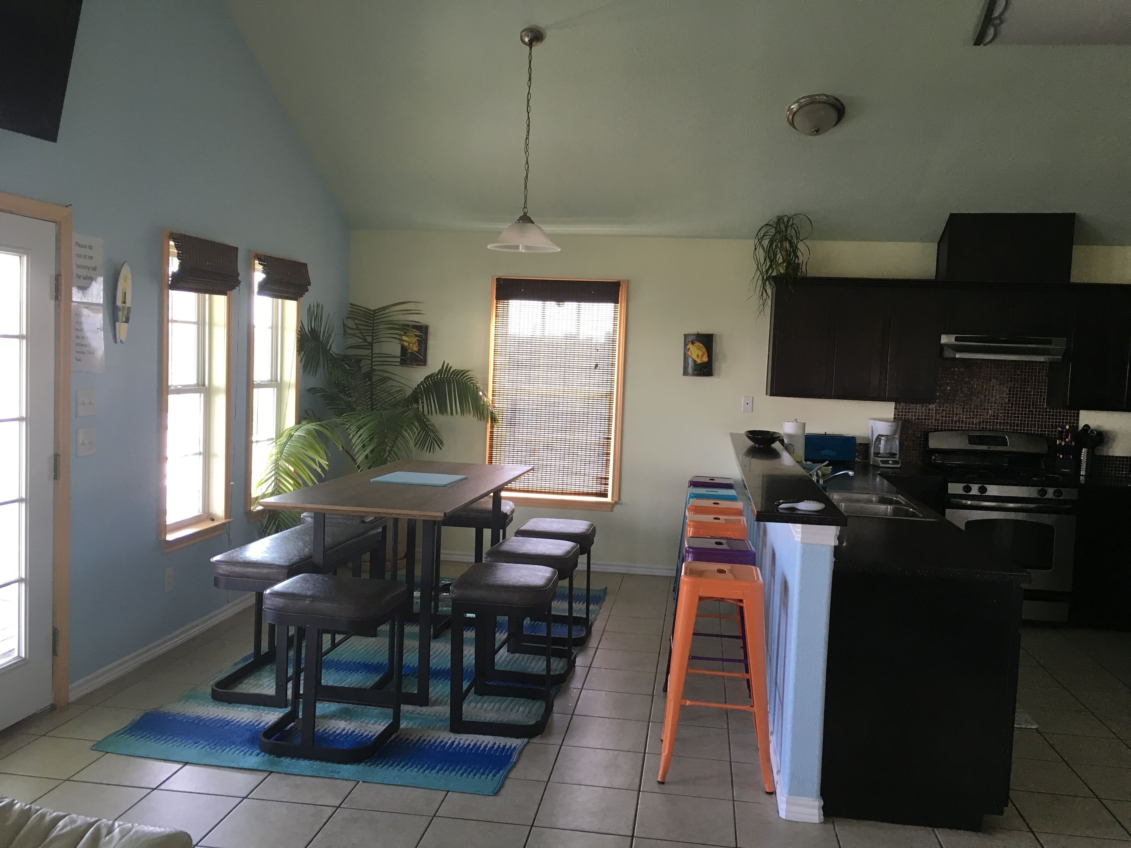 A kitchen with a dining area, a large window, and a ceiling fan.