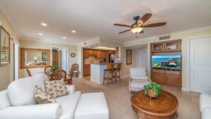 A spacious living room with a white sofa, a wooden coffee table, and a ceiling fan. - Amazing Gulf Views w/Private Beach, shelling & fishing on property! (Marco Island)