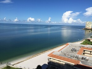 A coastal hotel with a view of the sea, a sandy beach, and a parking area.