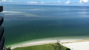 A view of a beach with clear water, a sandy shore, and a flagpole with flags. - Amazing Gulf Views w/Private Beach, shelling & fishing on property! (Marco Island)