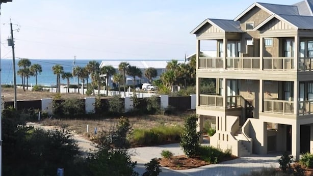 A beachfront property with a two-story building featuring balconies and a view of the ocean. - *PRIVATE BEACH*    *PRIVATE POOL*    *ELEVATOR*    *6 BEACH BIKES* (inlet beach)