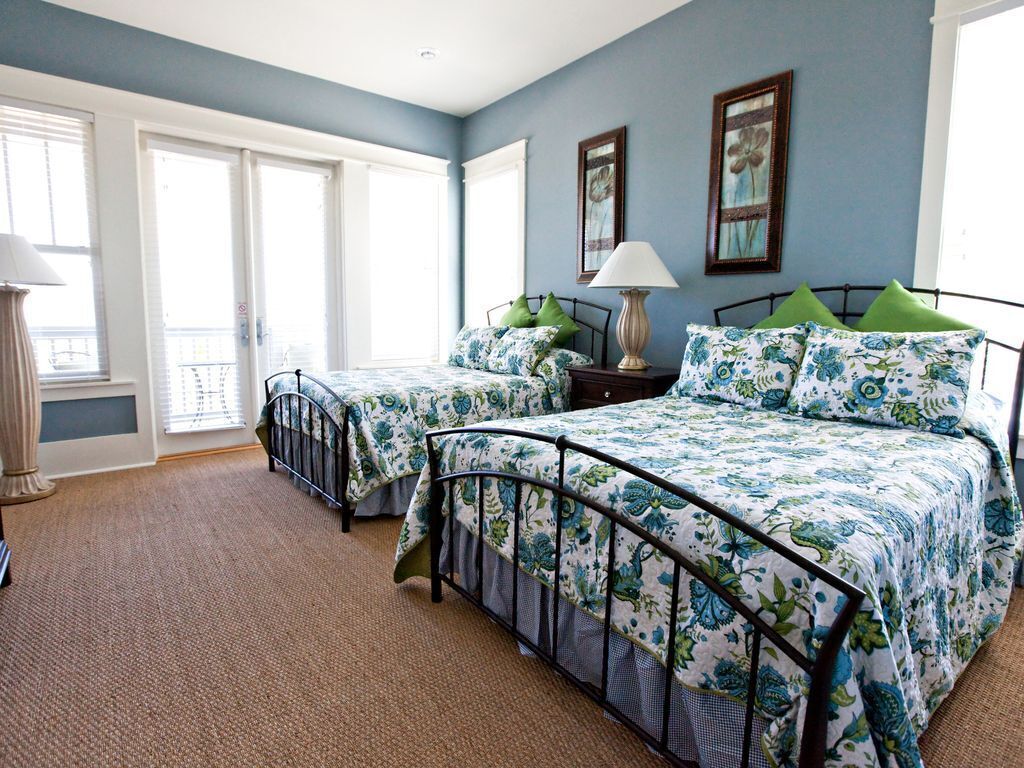 A bedroom with two beds, a window, and a door.