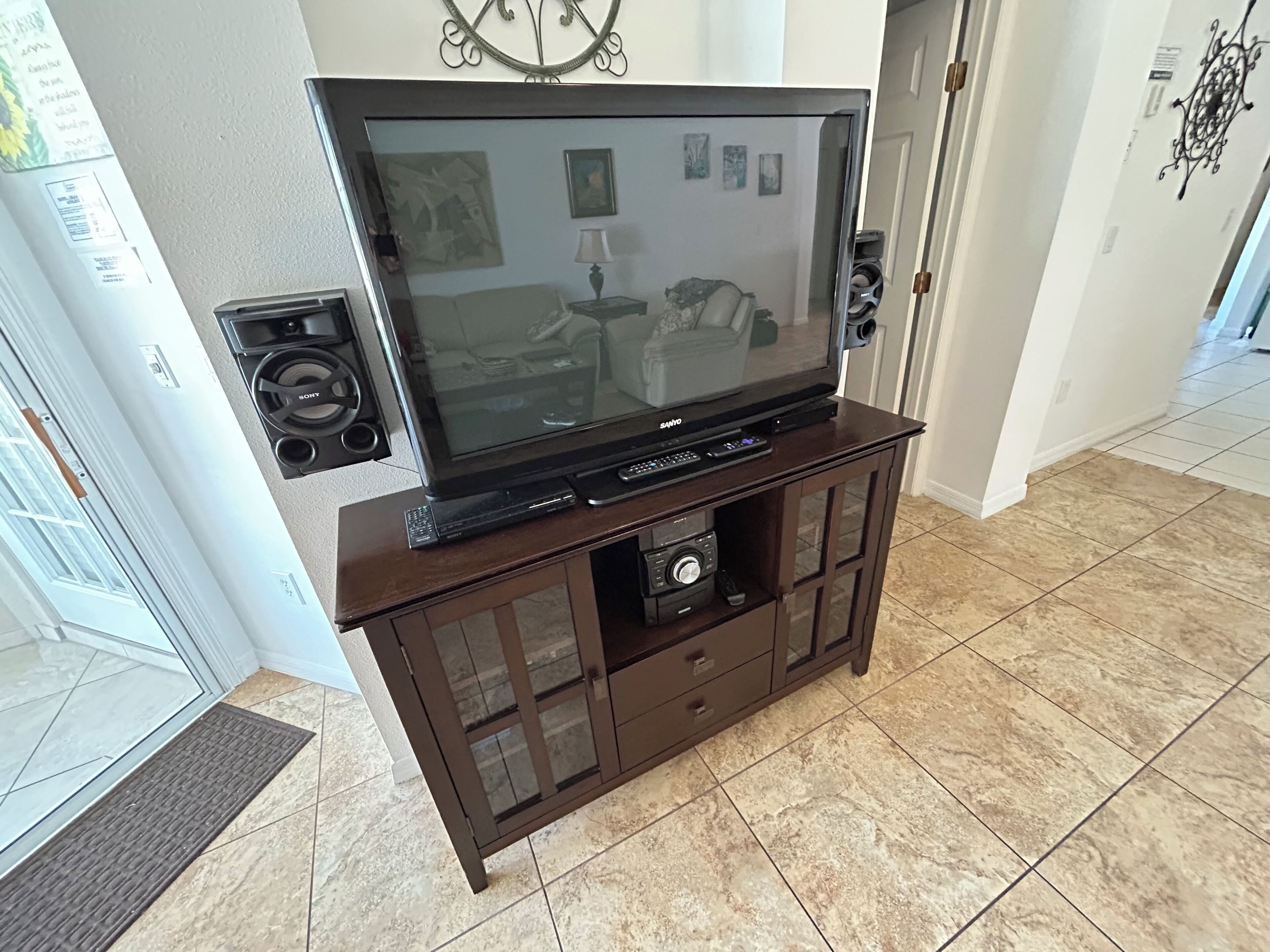 A living room with a large flat-screen TV on a wooden entertainment center, a fireplace, and a door leading to another room.