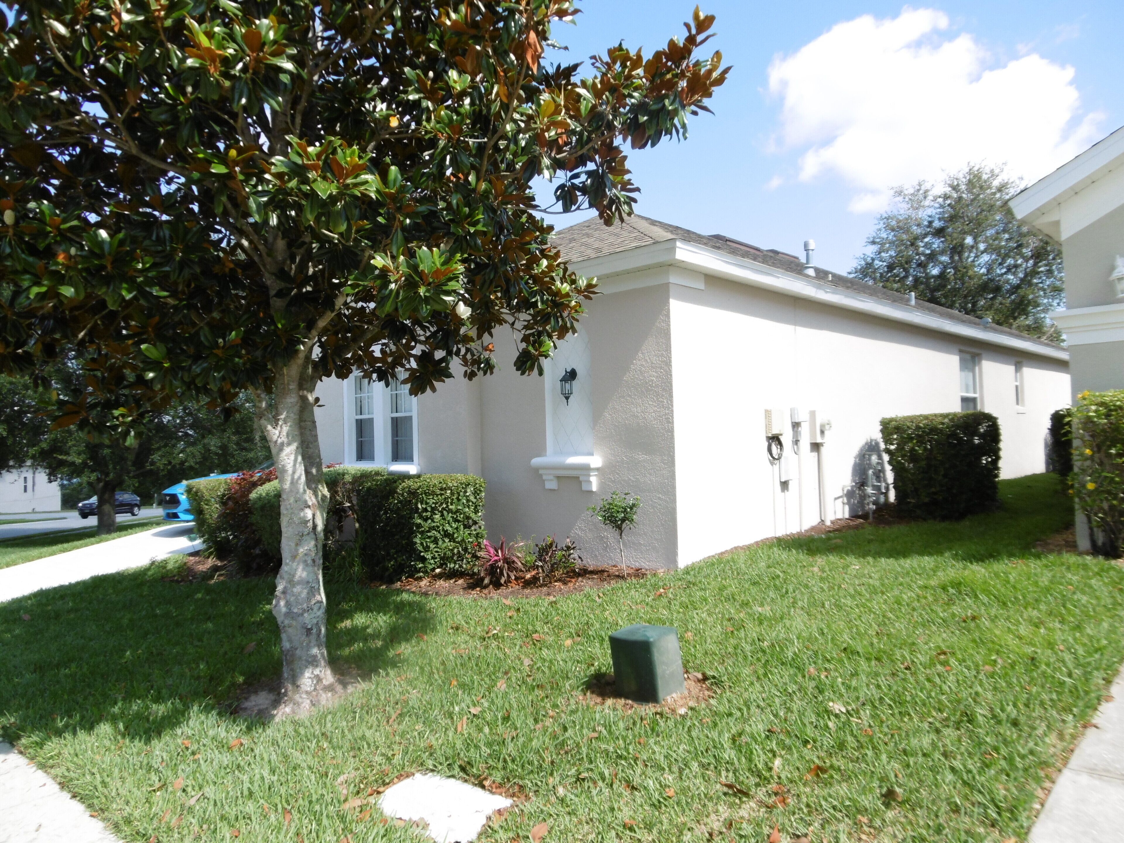 A residential house with a white exterior, a tree in the front yard, and a well-maintained lawn.