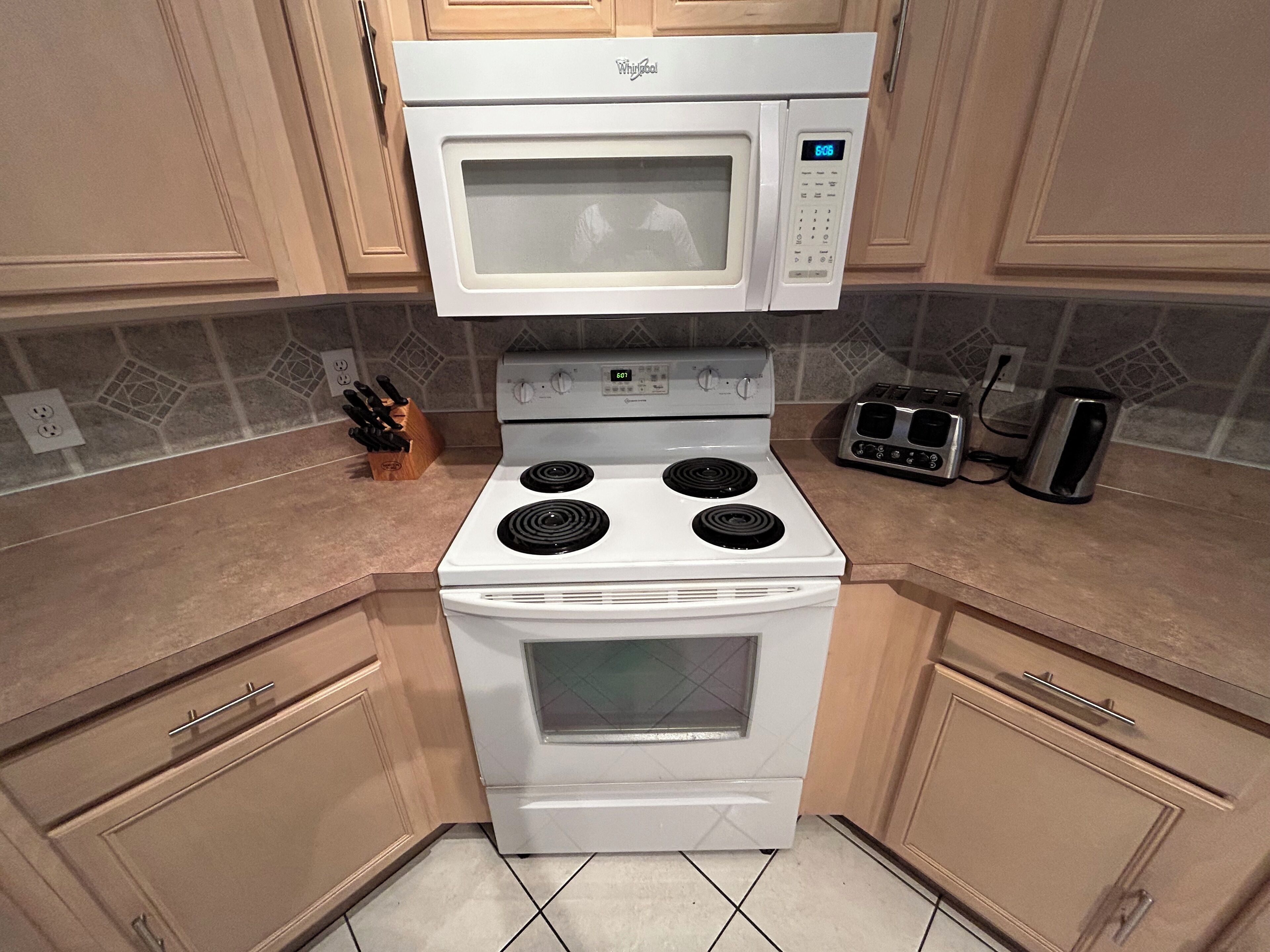 A kitchen with a white stove, microwave, and toaster.