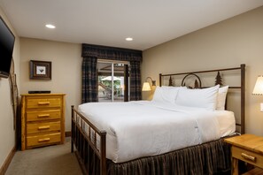 A hotel room with a bed, a wooden dresser, a television, and a view of the outdoors. - Montaneros 216 - 2 Bedroom Platinum (Vail)