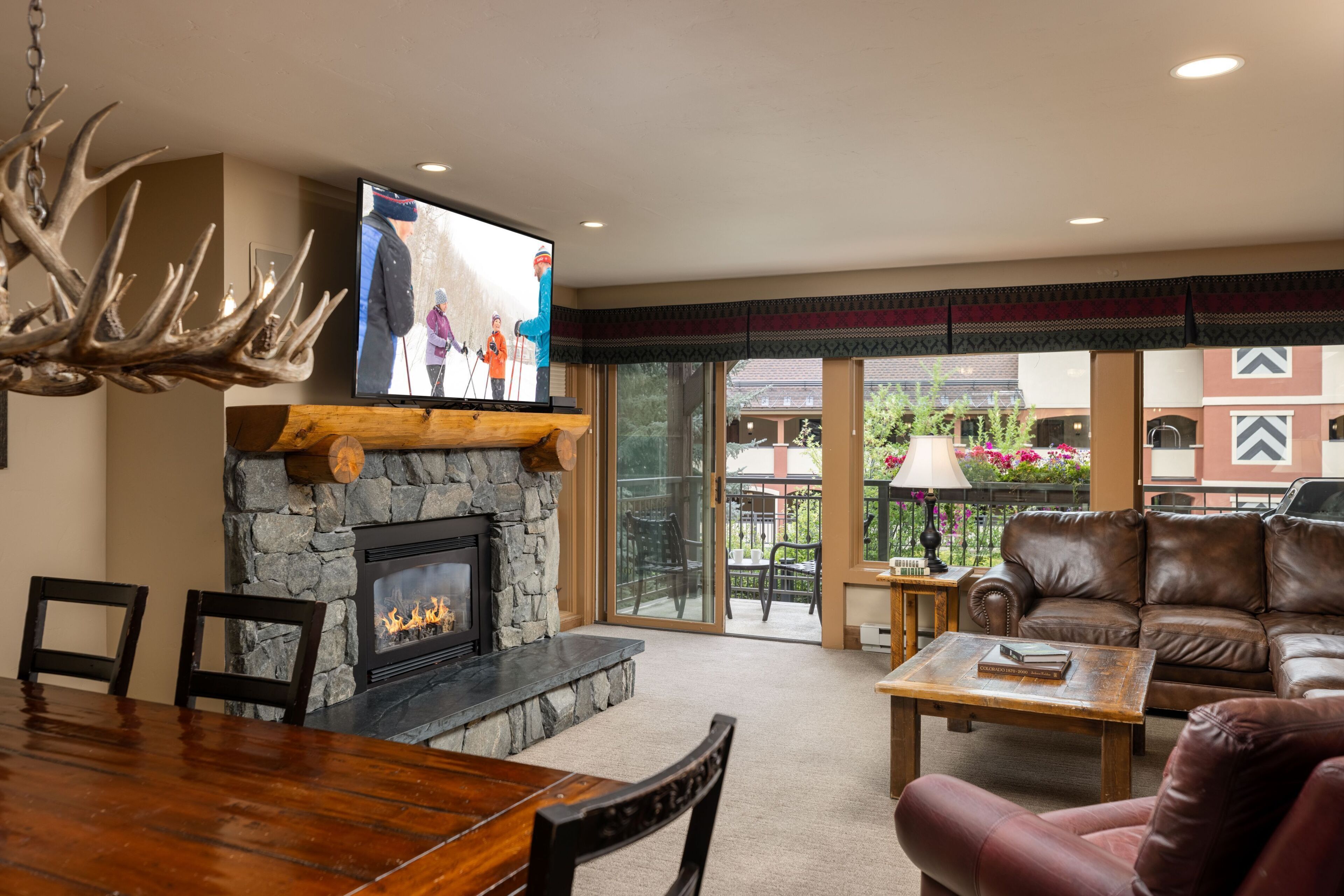 A living room with a stone fireplace, a television mounted above it, and a leather sofa.