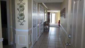 A hallway with a tiled floor, white doors, and a decorative wall with palm tree motifs. - Stunning Gulf View Unit.......Last Minute Discounts Available! (Destin)