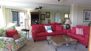 A living room with a red sofa, a floral armchair, and a glass coffee table. - Stunning Gulf View Unit.......Last Minute Discounts Available! (Destin)