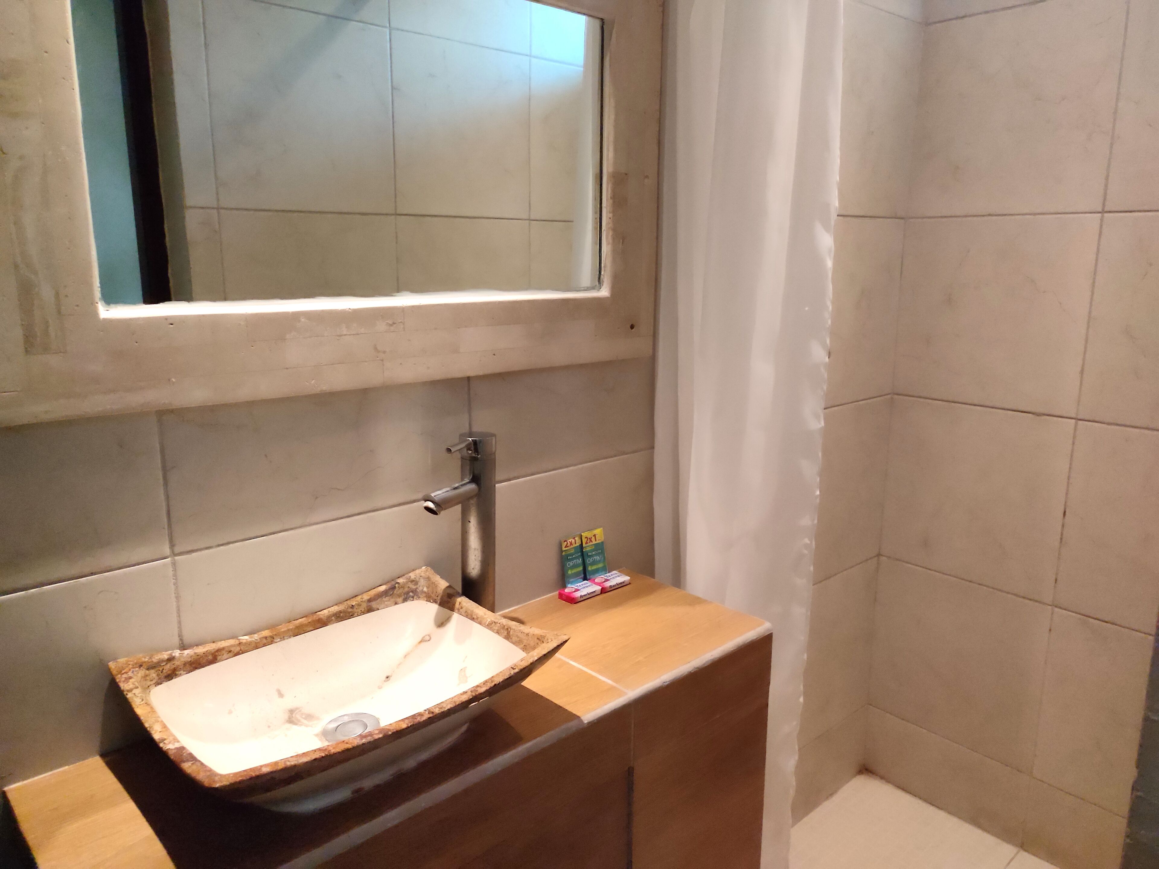 A bathroom with a rectangular sink, a mirror above it, and a shower curtain.