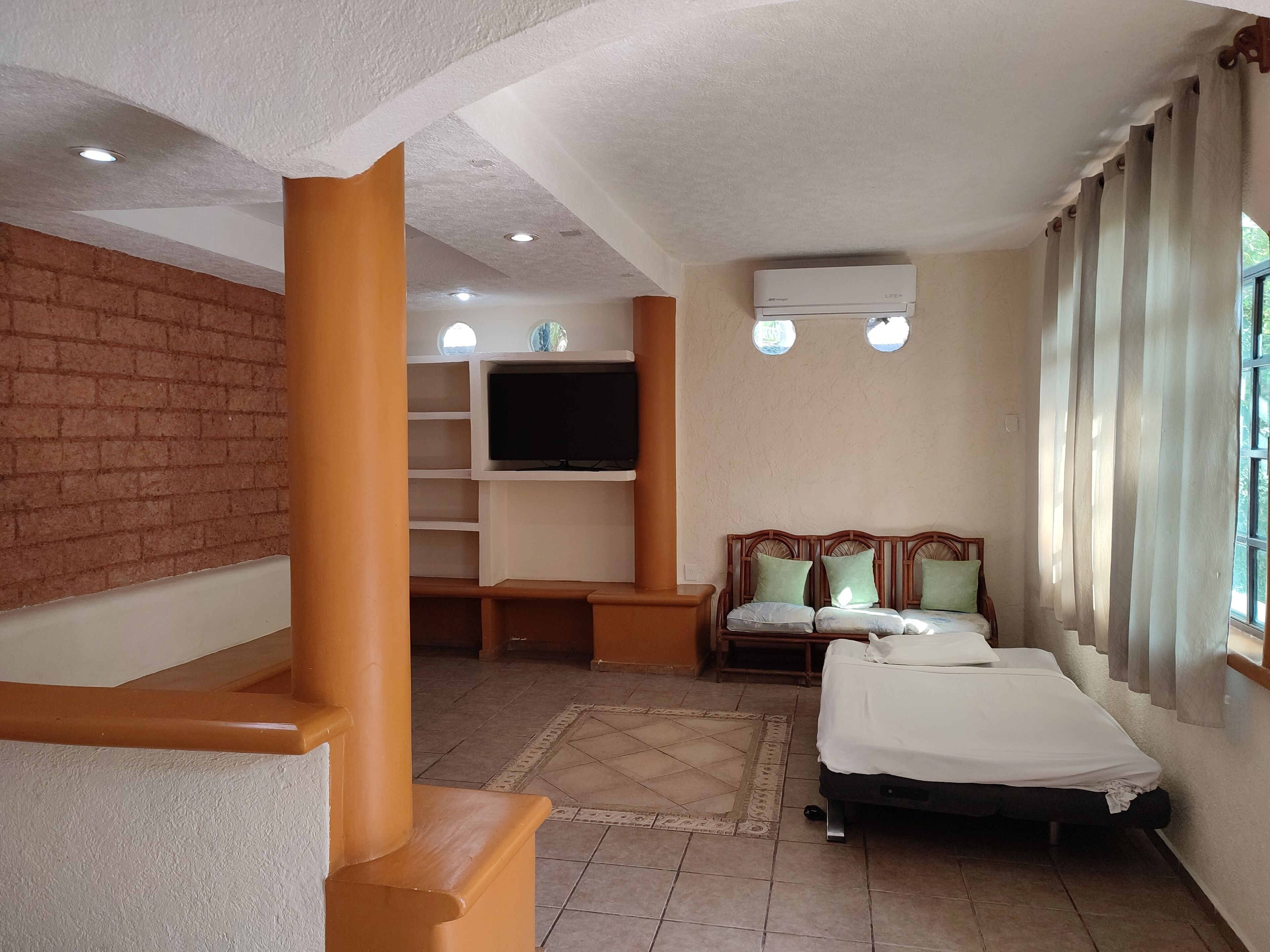 Une chambre d’hôtel équipée d’une télévision, d’un lit, d’un canapé et d’une fenêtre avec des rideaux.