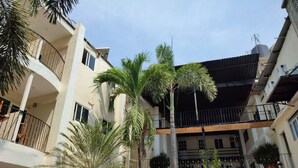 A multi-story residential building with balconies, palm trees, and a clear sky. - Hotel Ashly (Acapulco)