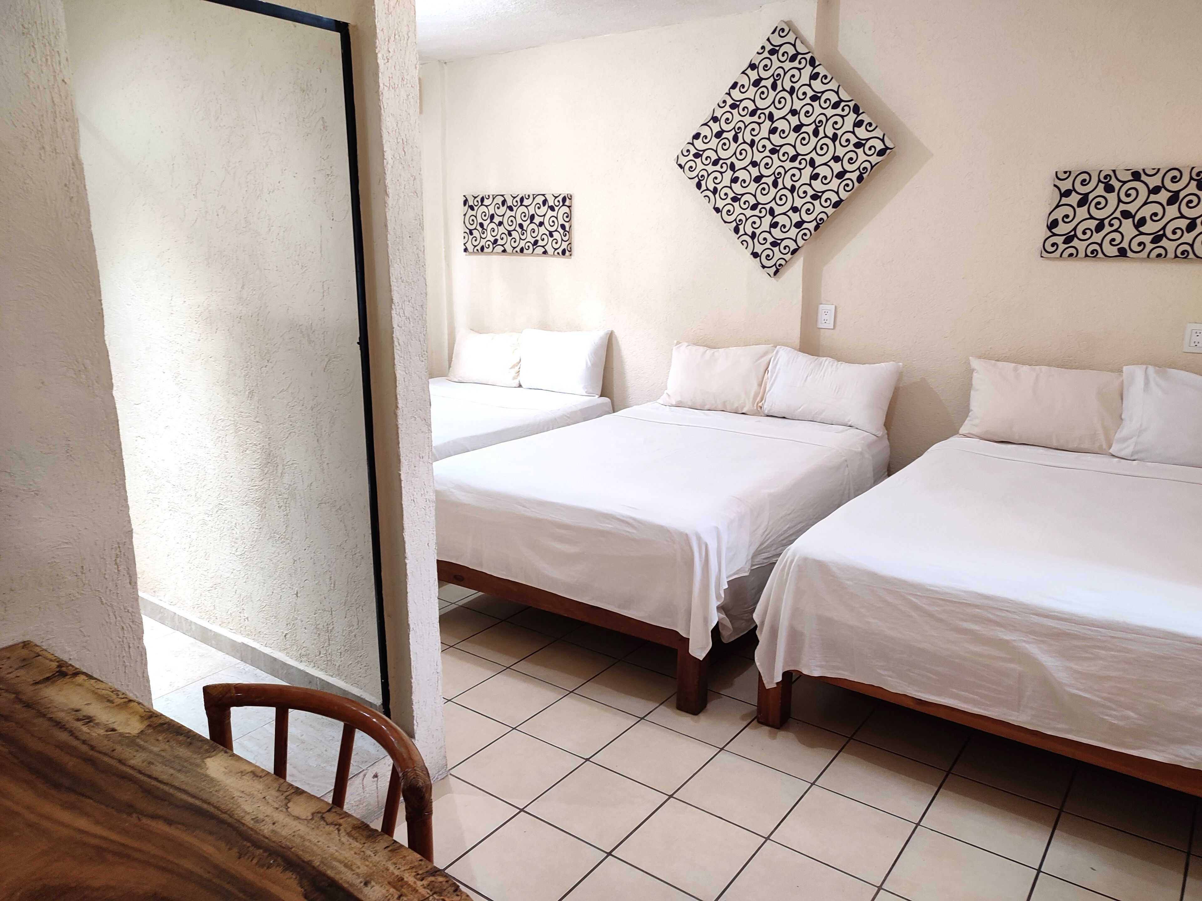 Ein Zimmer mit zwei Betten, einem Holztisch und einem Stuhl.
