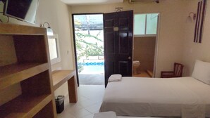 A hotel room with two beds, a wooden shelf, a small trash bin, and a view of the outside. - Hotel Ashly (Acapulco)