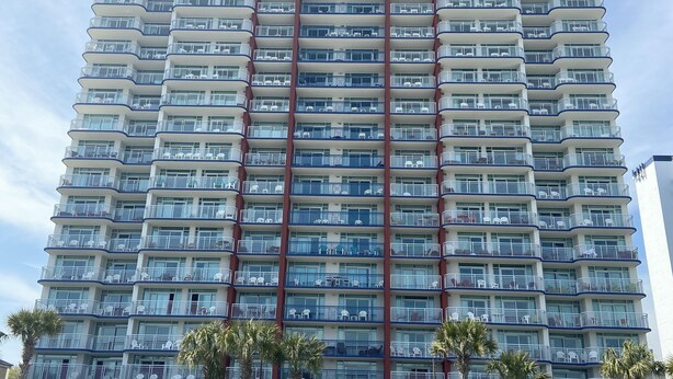 A high-rise hotel with multiple balconies and a beachside location.