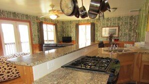 Una cocina con encimeras de granito, estufa y ventilador de techo.