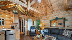 A log cabin interior with a kitchen, dining area, and living room.