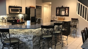 A modern kitchen with granite countertops, stainless steel appliances, and a central island with bar stools.