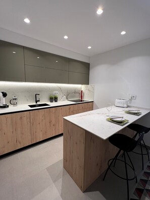 A modern kitchen with wooden cabinets, a marble countertop, and a dining area with a white table and black chairs.