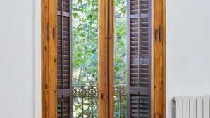 A wooden double door with glass panels and shutters, a radiator below, and a wooden table to the left.