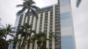 A high-rise hotel with multiple balconies and palm trees in the foreground. - Stay On The Beach In Makaha   (Waianae)